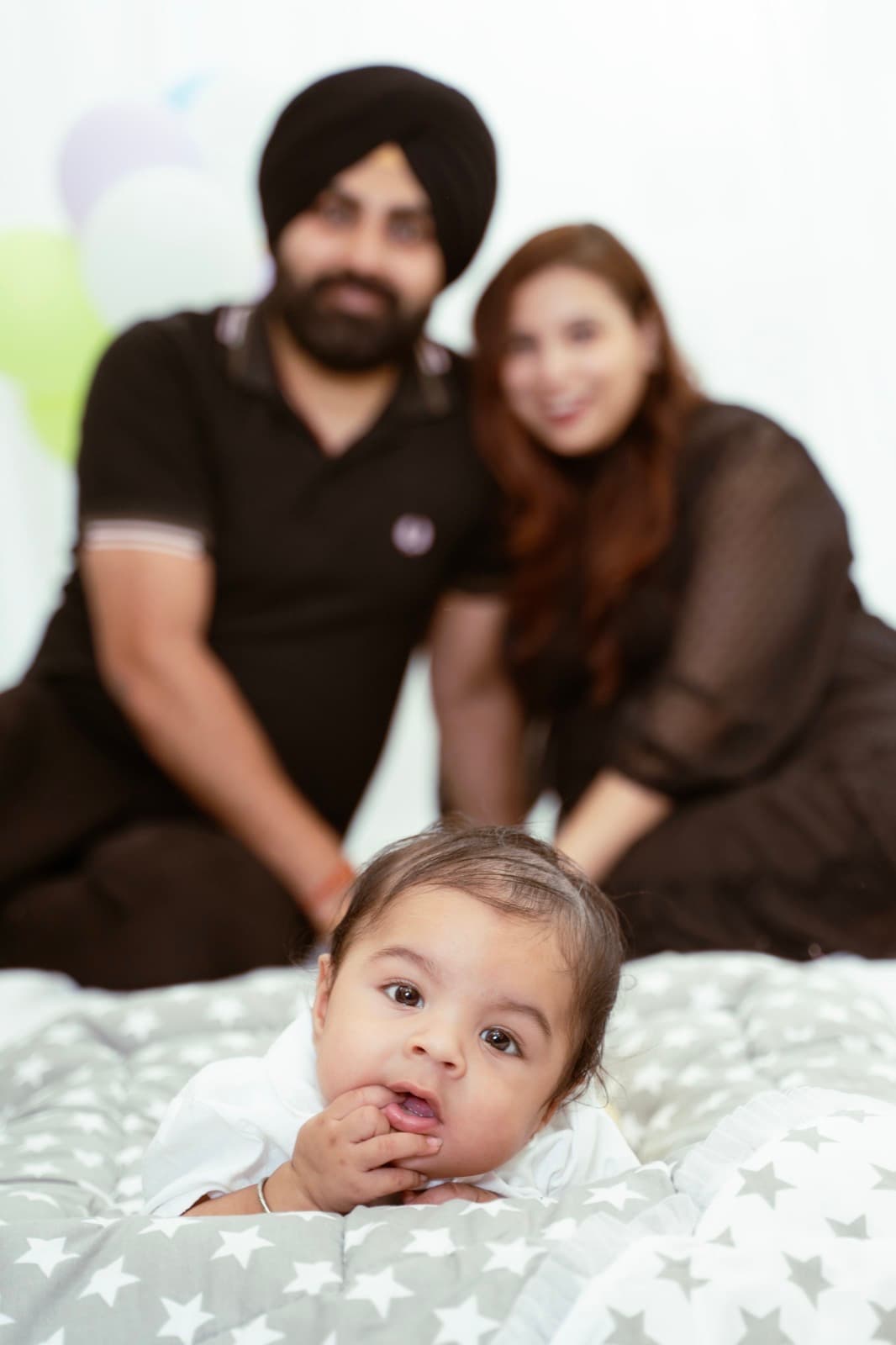 Parents smiling at their baby, who is looking straight at the camera