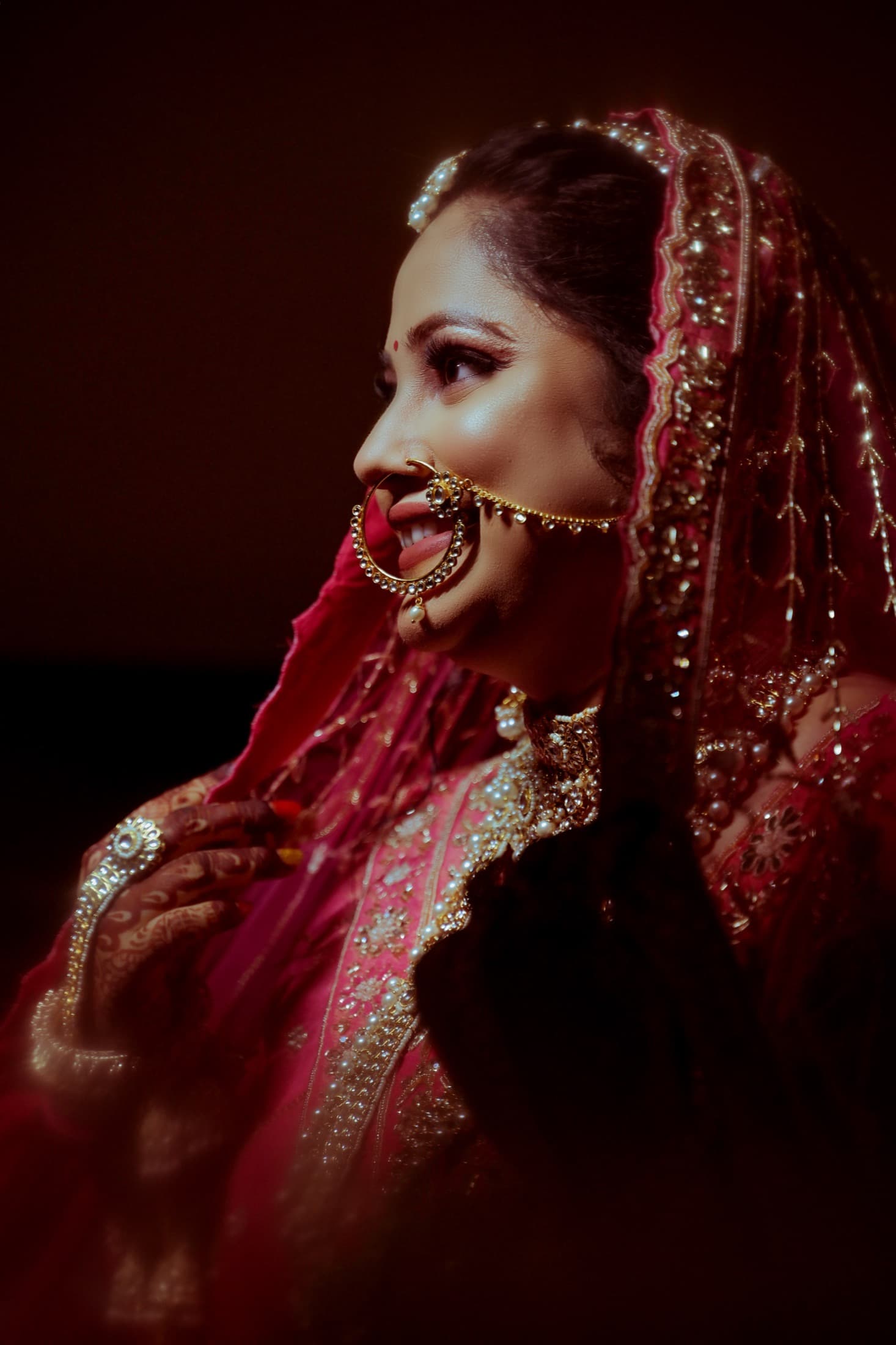 Close-up, low-light portrait of a bride in profile, softly blurred foreground