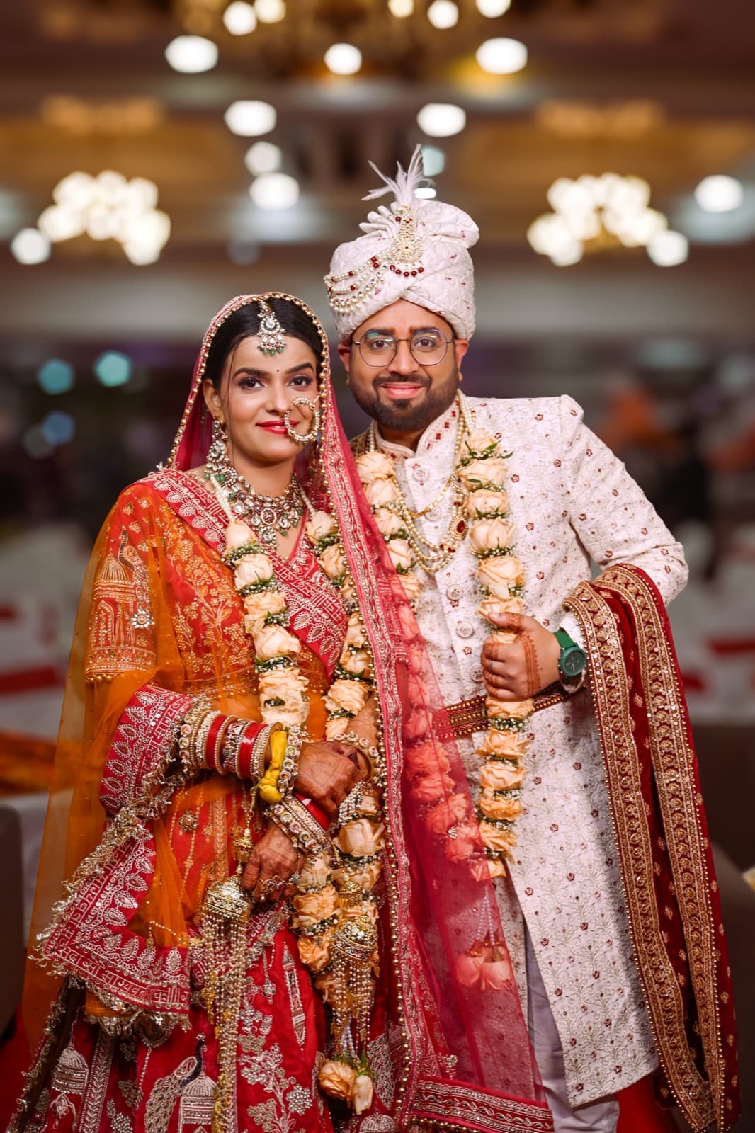 Bride and groom smiling together, adorned with rose garlands at their wedding