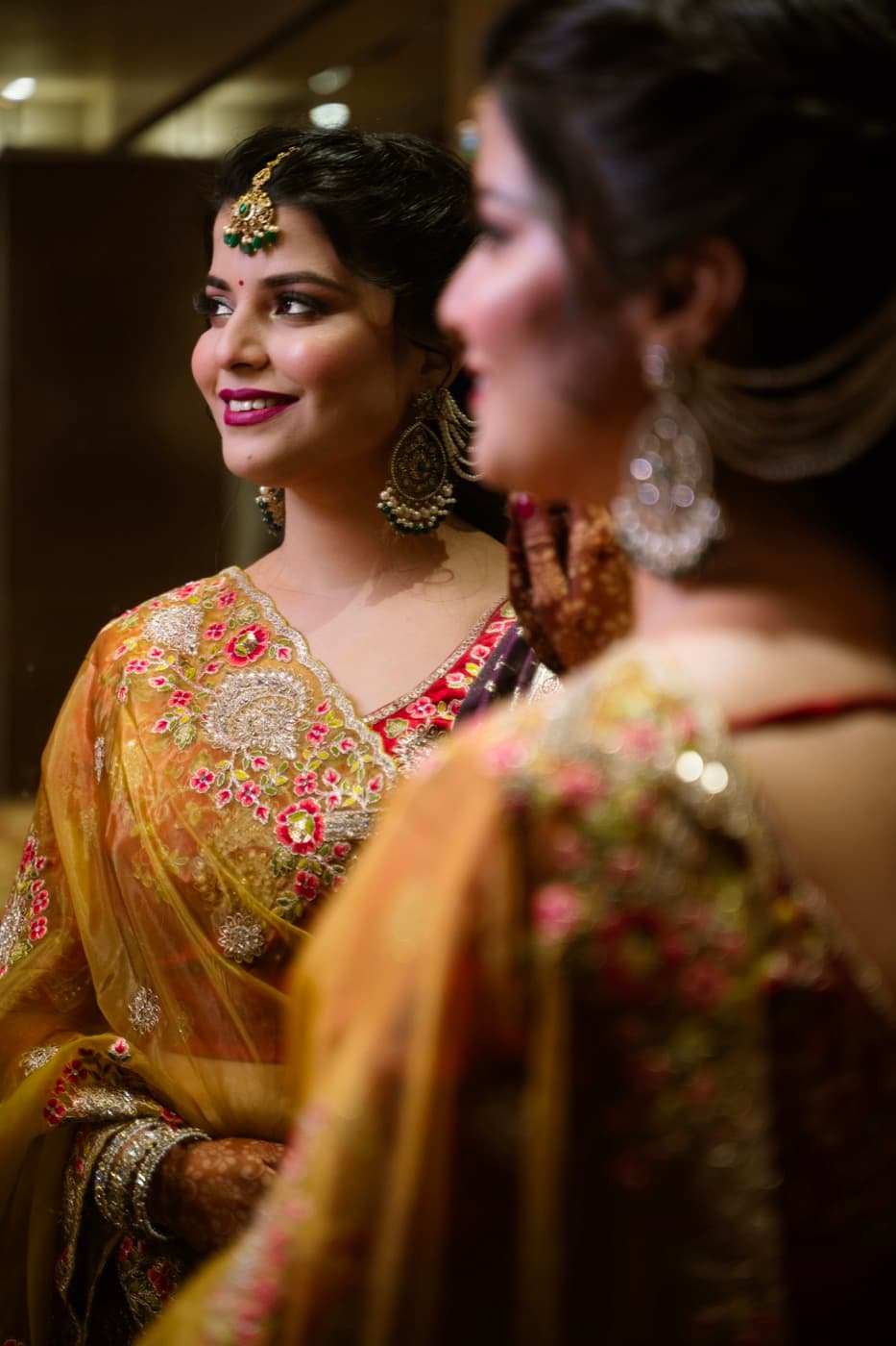 Close-up bridal portrait with a maang tikka and gold-embroidered dupatta