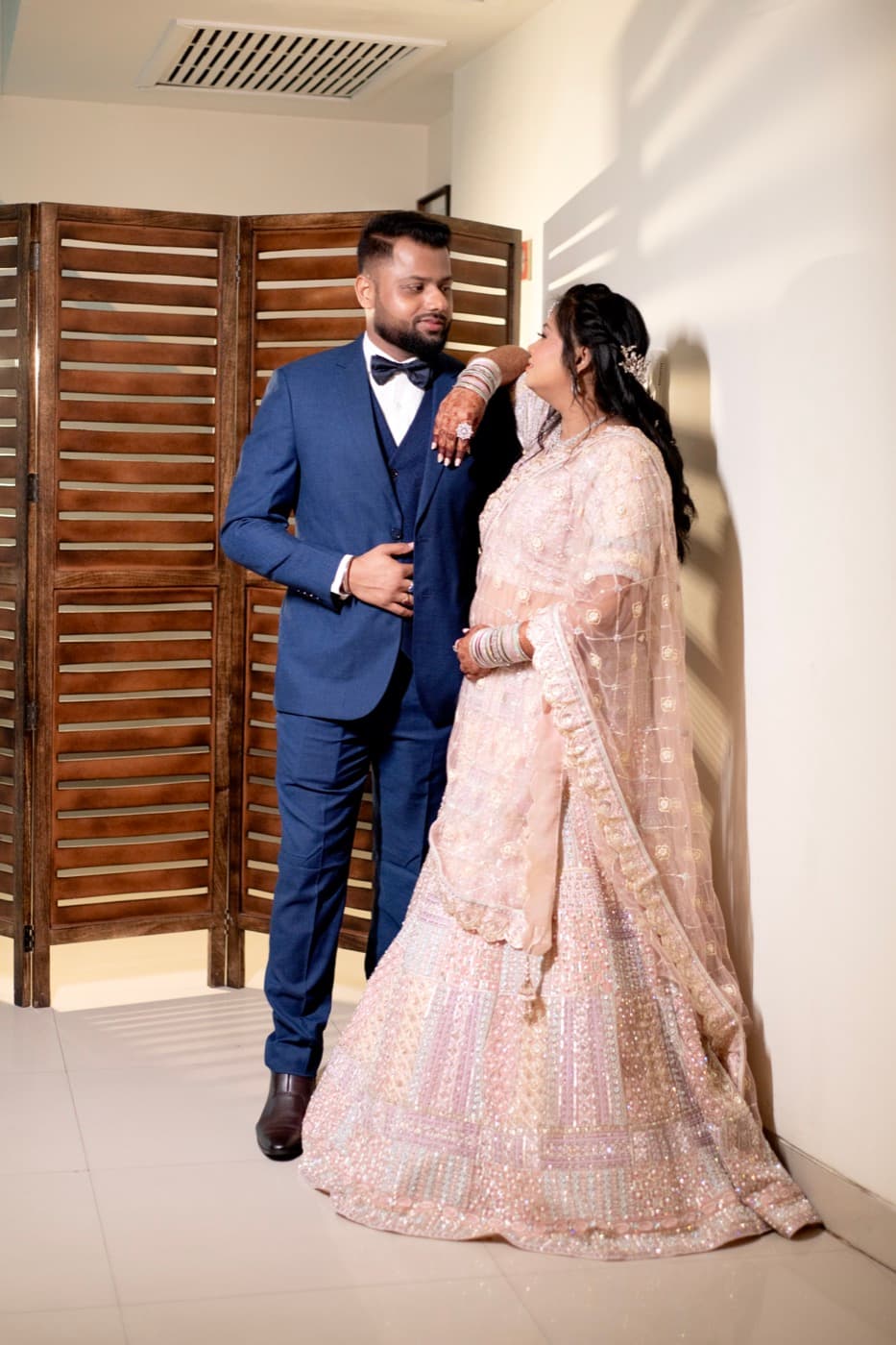 Couple standing close together in a doorway, smiling at each other