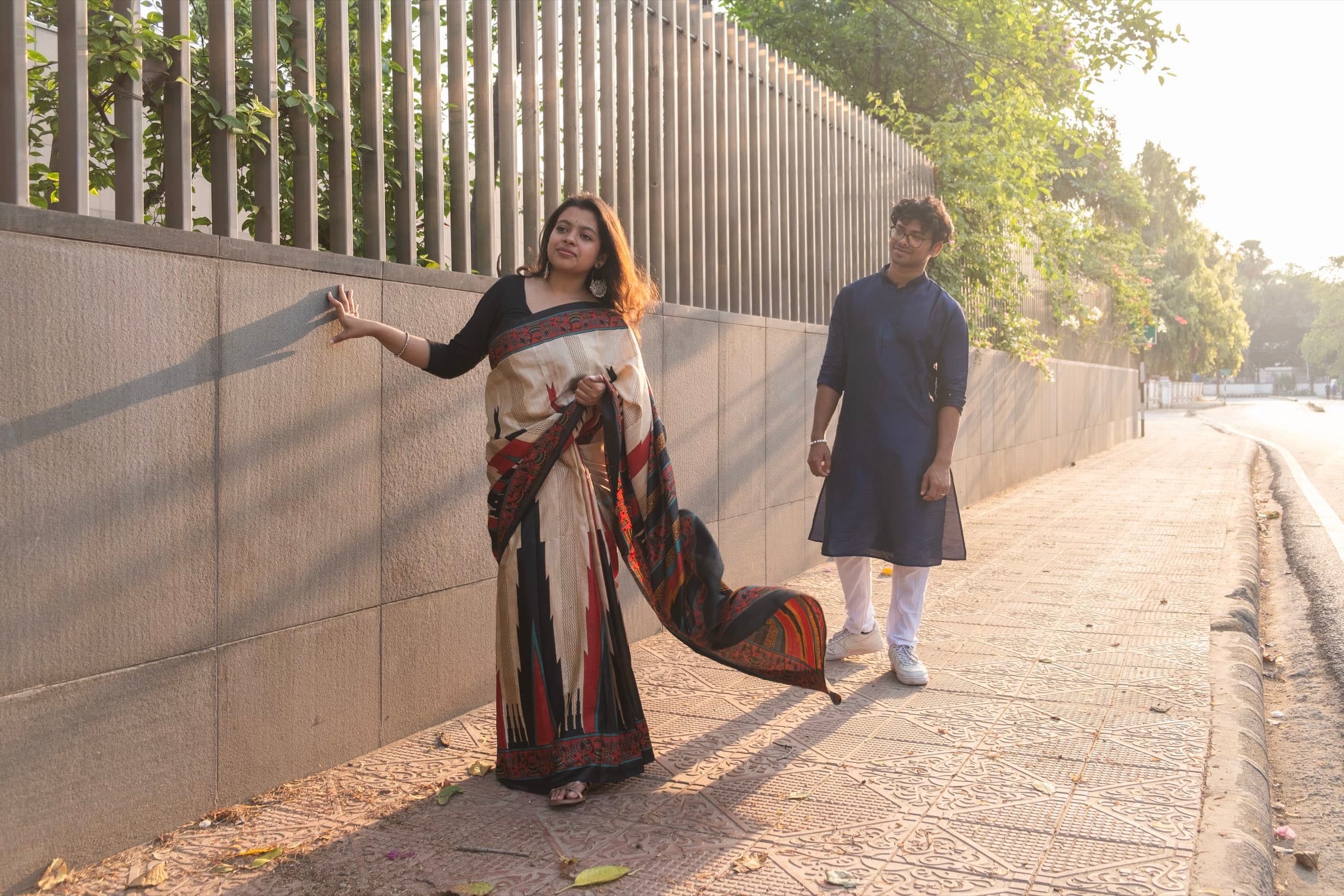 A couple walking together along a sunlit garden wall